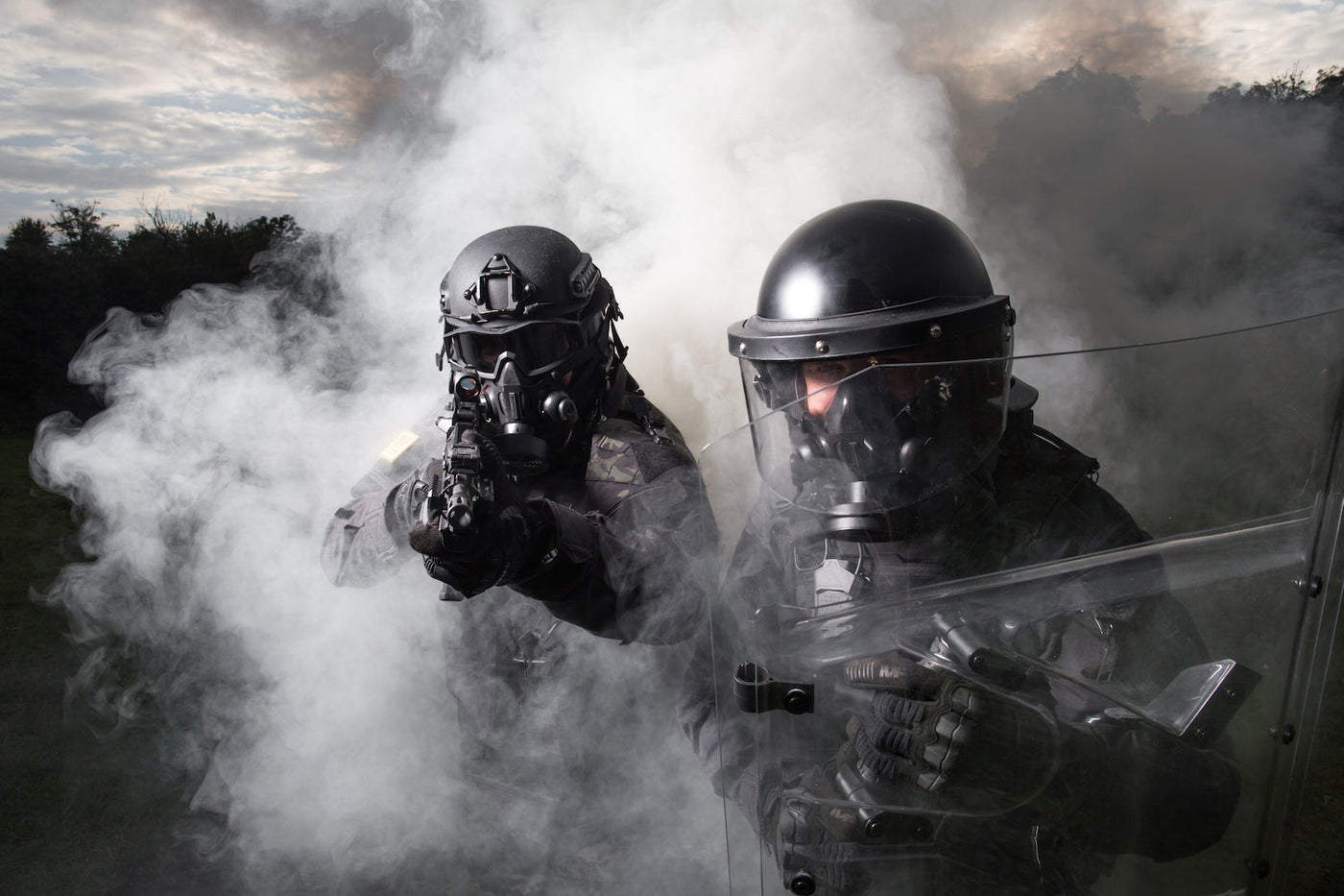 Two SWAT members deploying tear gas while wearing the Tactical Air-Purifying Respirator mask (TAPR)